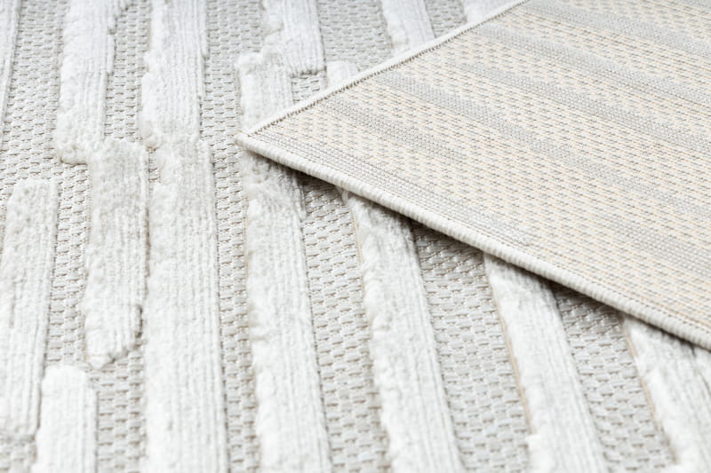 Dywan Santi Sznurkowy w odcieniu beżowym, z falistym wzorem. Widoczny fragment z teksturą i delikatnym splotem, leżący na jasnym tle. Produkt dostępny w różnych rozmiarach, idealny do wnętrz.