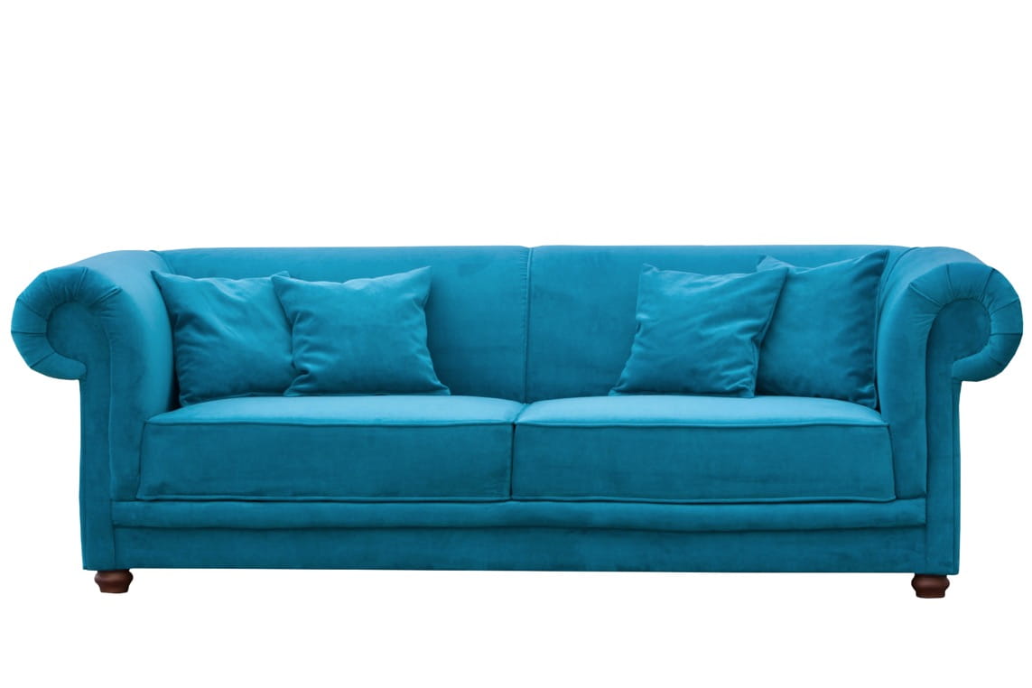 Trzyosobowa sofa Chesterfield w błękitnym kolorze, z materiału tapicerskiego, z dekoracyjnym, zaokrąglonym oparciem i jasnymi poduszkami. Ujęcie frontalne, produkt ustawiony na stabilnych nogach. Wymiary: 210x105x80 cm.