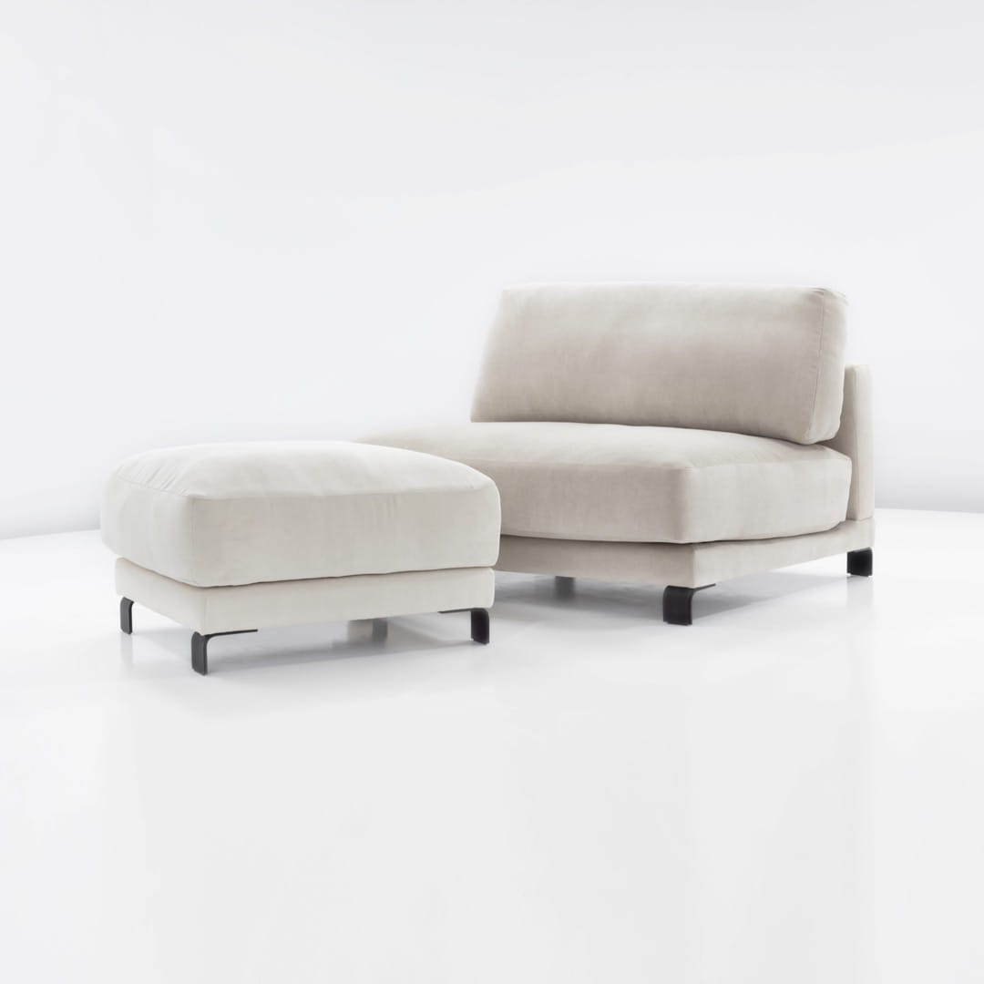 Puf Harvey w kolorze jasnym, wykonany z miękkiego materiału. Zestaw składa się z pufa i sofy w stylu minimalistycznym, z prostymi, czarnymi nogami. Ujęcie frontalne, produkt stoi na białym tle.