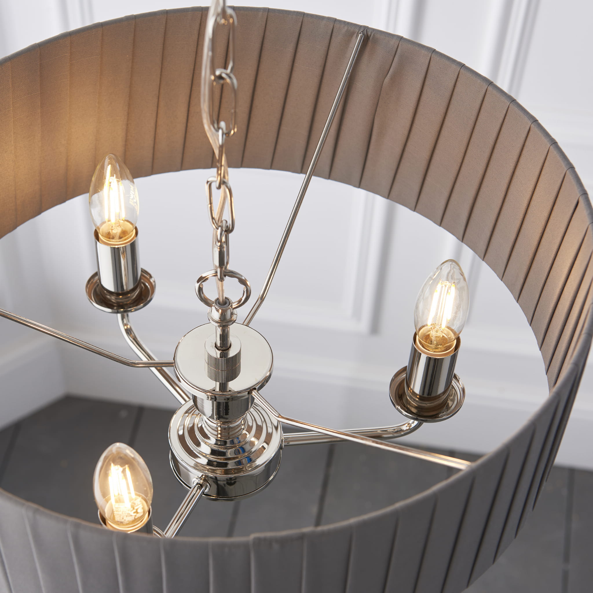 Lampa sufitowa wisząca Highclere z niklowanym stelażem i tkaninowym kloszem w jasnoszarym kolorze. Widok z góry na cztery źródła światła, metalowe mocowania i detalizowany klosz z fałdami. Produkt zawieszony na łańcuchu, w prostym, jasnym tle.