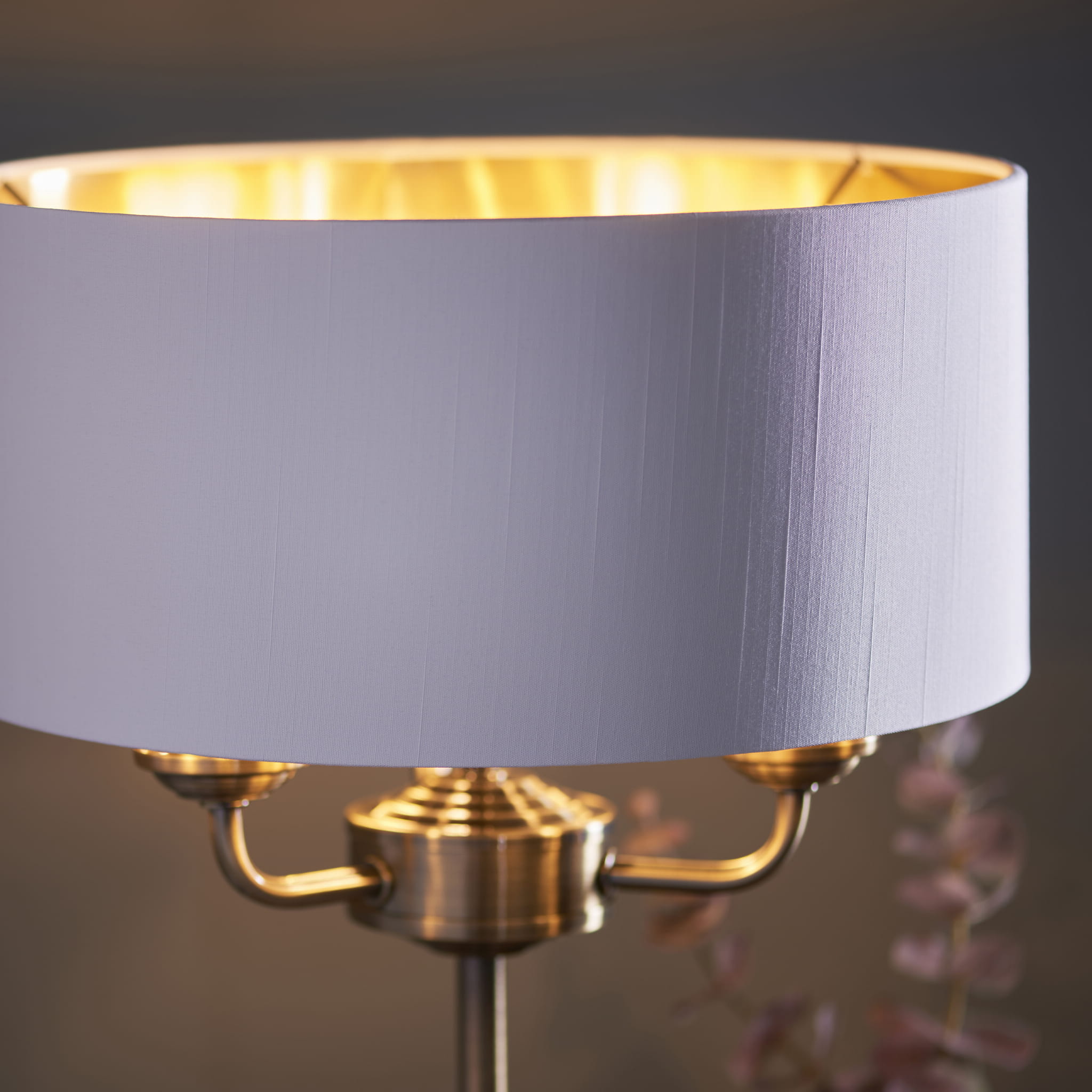 Lampa stołowa Highclere w mosiężnej podstawie z tkaninowym kloszem w kolorze białym. Widok z boku, eksponujący elegancką, prostą formę oraz detal tekstury klosza. Tło z miękkim rozmyciem, podkreślającym produkt. Wysokość lampy: 50 cm.
