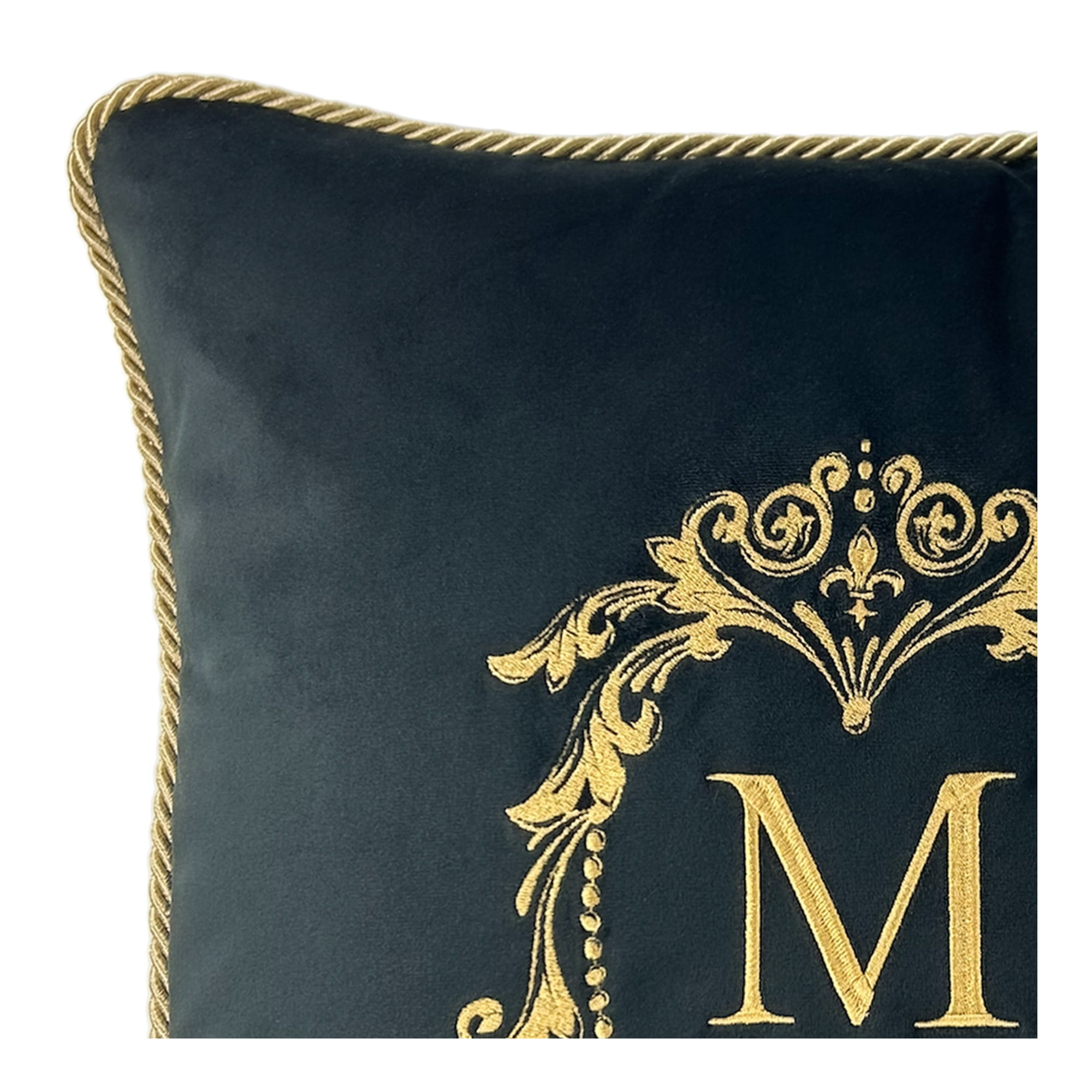 Poduszka dekoracyjna w kolorze ciemnoniebieskim, z haftem w kolorze złotym, przedstawiająca elegancki monogram M oraz ozdobne wzory. Narożniki ozdobione plecionką. Produkt leżący, widok z przodu.