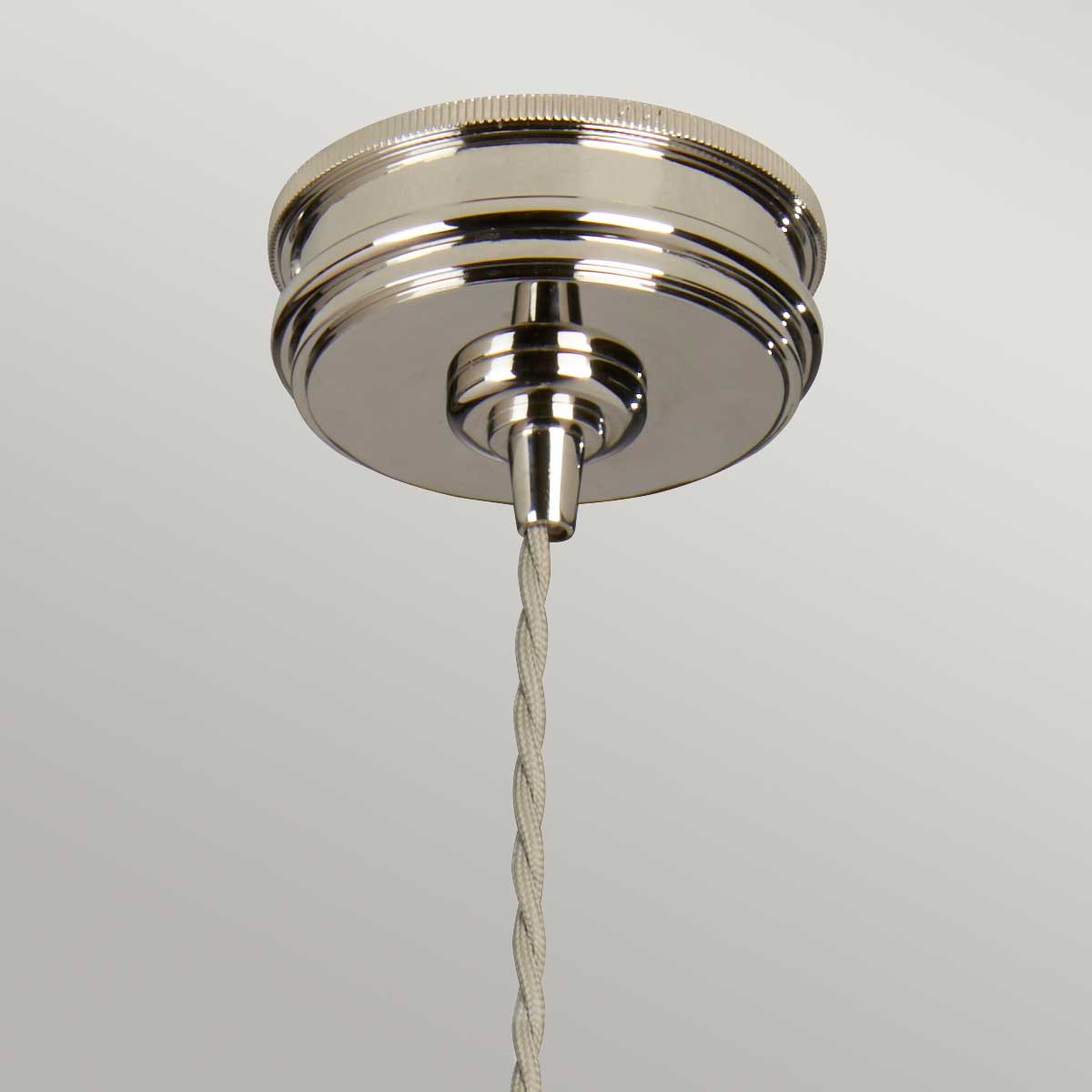 Osłona sufitowa lampy wiszącej Ravello w kolorze niklu, z metalicznym wykończeniem i detalami. Widoczny także pleciony kabel w jasnym odcieniu. Kąt ujęcia: z dołu. Produkt wiszący w minimalistycznym otoczeniu.