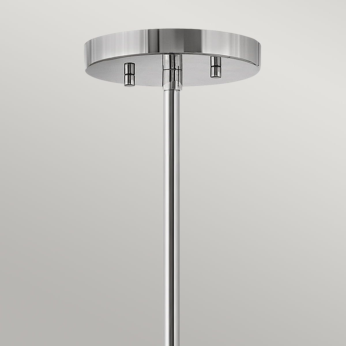 Nowoczesna lampa wisząca Gela w kolorze polerowanego niklu, z okrągłą podstawą. Ujęcie z góry ukazuje długą chromowaną rurę mocującą. Prosty design, idealna do przestrzeni nowoczesnych. Tło jednolite, podkreślające elegancję produktu.
